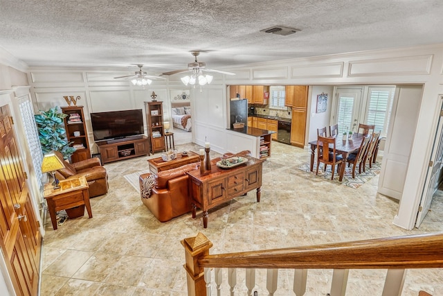 3026 Dees Cir, Sealy, TX 77474 - living room with crown molding, a textured ceiling, visible vents, a decorative wall, and ceiling fan