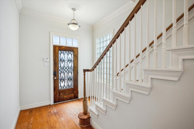 entryway featuring baseboards, ornamental molding, stairs, and wood finished floors