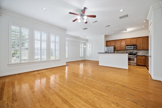 unfurnished living room featuring a wealth of natural light, visible vents, ceiling fan, and crown molding