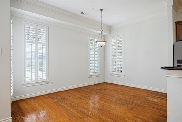 unfurnished dining area with baseboards, visible vents, wood finished floors, and ornamental molding