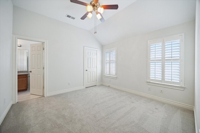 unfurnished bedroom with connected bathroom, vaulted ceiling, light carpet, baseboards, and visible vents
