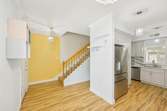 7463 Brompton St Unit 7463, Houston, TX 77025 - kitchen featuring appliances with stainless steel finishes, light wood-type flooring, baseboards, a sink, and crown molding
