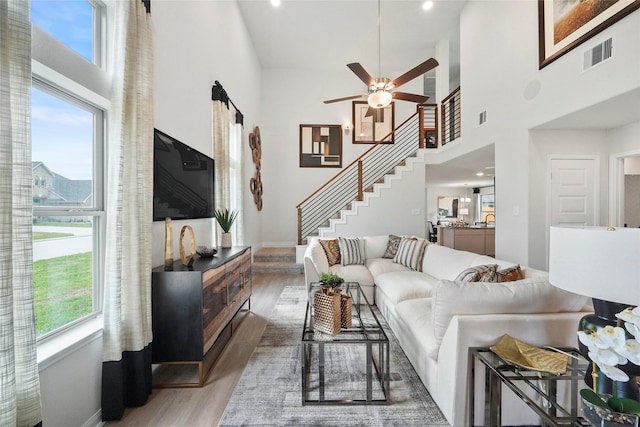 living room featuring light wood-style floors, stairs, visible vents, and a wealth of natural light