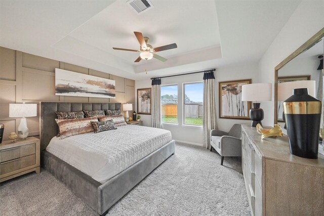 bedroom featuring ceiling fan, visible vents, carpet floors, a raised ceiling, and baseboards