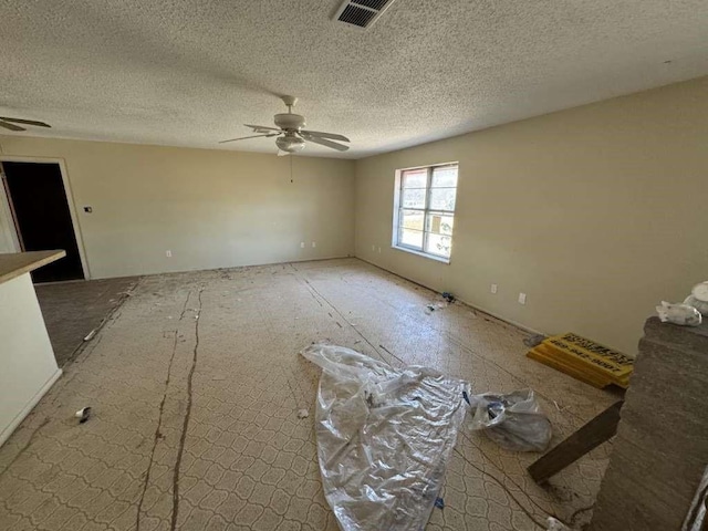 empty room featuring visible vents, ceiling fan, and a textured ceiling