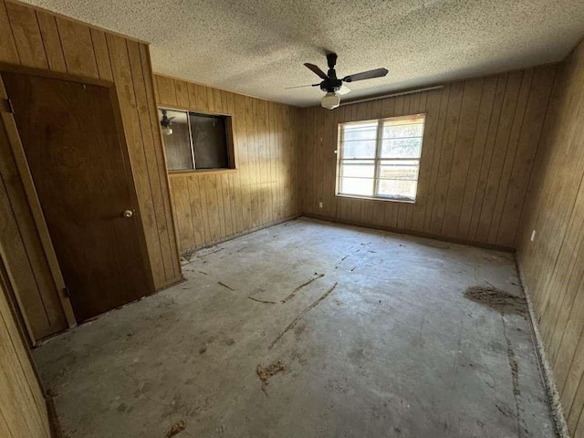 unfurnished room featuring wooden walls and ceiling fan
