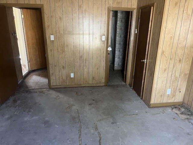 empty room featuring wooden walls and unfinished concrete flooring