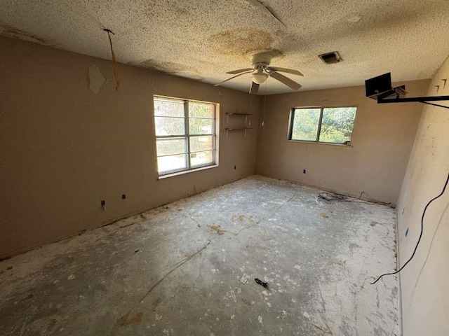 empty room featuring a textured ceiling, ceiling fan, and visible vents