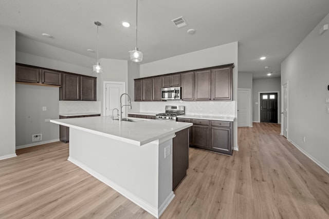 kitchen featuring dark brown cabinetry, visible vents, stainless steel appliances, light wood finished floors, and a sink