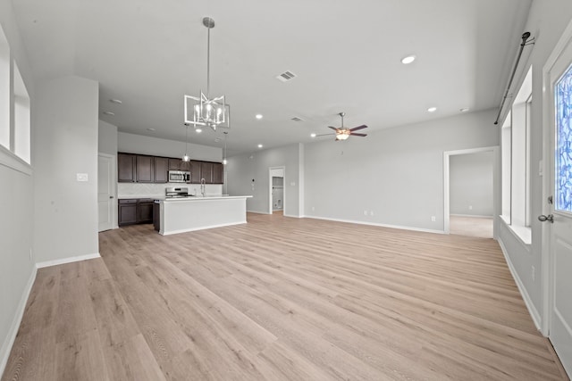 unfurnished living room featuring light wood-style flooring, ceiling fan with notable chandelier, a healthy amount of sunlight, and recessed lighting