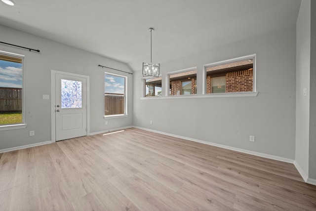 unfurnished dining area featuring baseboards, vaulted ceiling, a chandelier, and wood finished floors