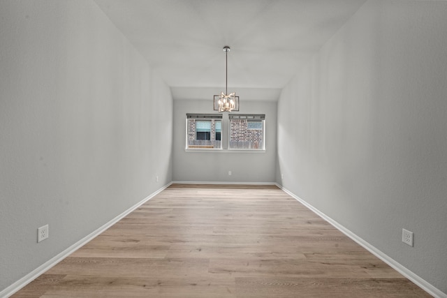 unfurnished dining area with a chandelier, wood finished floors, and baseboards