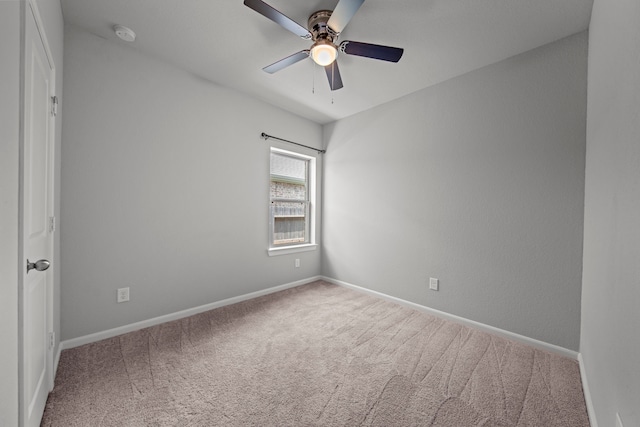 carpeted empty room featuring ceiling fan and baseboards