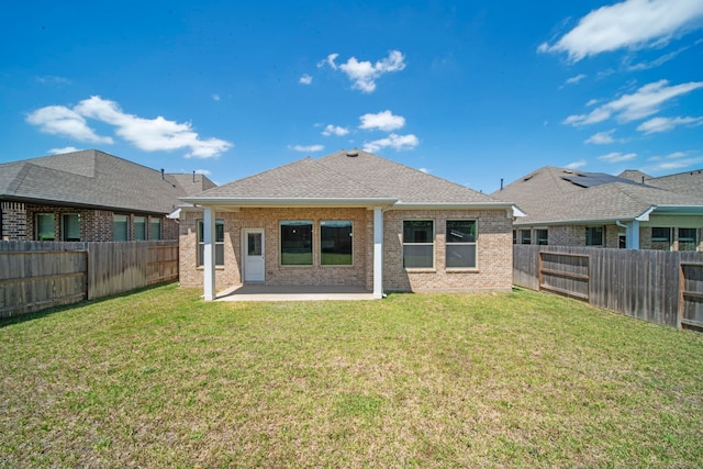 rear view of property featuring brick siding, a fenced backyard, and a lawn