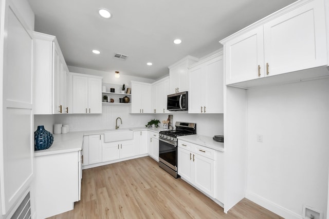 300 Narcissus Rd, Clear Lake Shores, TX 77565 - kitchen with light wood-style flooring, open shelves, visible vents, appliances with stainless steel finishes, and a sink