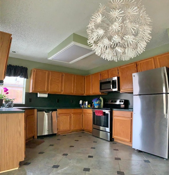 kitchen with a textured ceiling, dark countertops, and stainless steel appliances