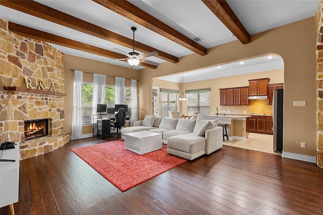 321 Westwood Dr, League City, TX 77573 - living room with arched walkways, a fireplace, light wood-style flooring, ceiling fan, and beam ceiling