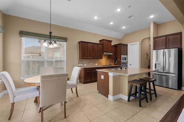 321 Westwood Dr, League City, TX 77573 - kitchen with appliances with stainless steel finishes, under cabinet range hood, tasteful backsplash, a kitchen island with sink, and light stone counters