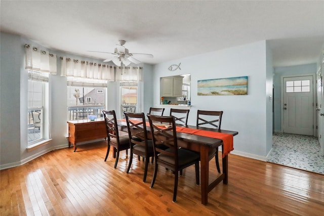 dining room with baseboards, ceiling fan, and light wood-style flooring
