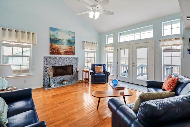 living area with a premium fireplace, high vaulted ceiling, ceiling fan, and wood finished floors