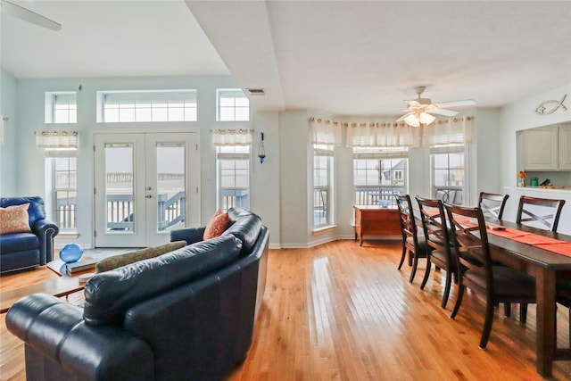 living room featuring light wood-style floors, a ceiling fan, a wealth of natural light, and french doors