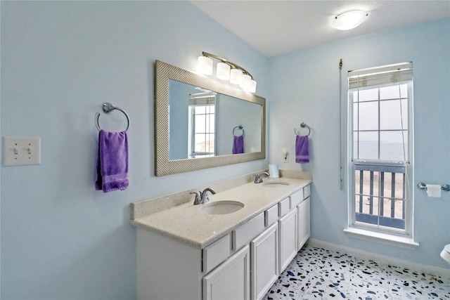 bathroom featuring double vanity, baseboards, and a sink