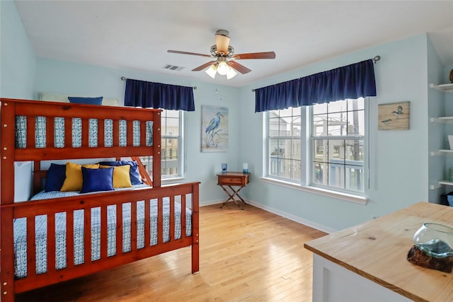 bedroom featuring baseboards, visible vents, multiple windows, and wood finished floors