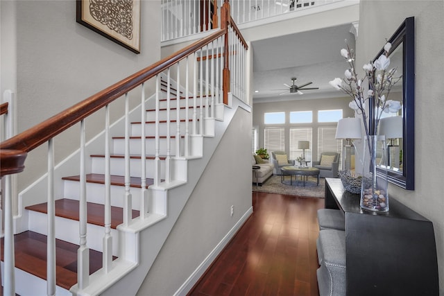 staircase with wood finished floors, ceiling fan, and ornamental molding