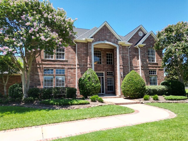view of front of home with a front lawn and brick siding
