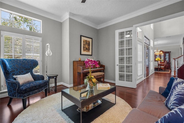 living room with baseboards, ornamental molding, a chandelier, a textured ceiling, and wood finished floors