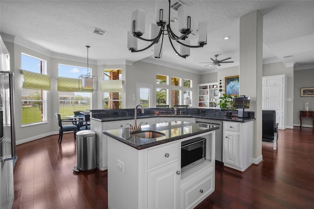 kitchen with a sink, ornamental molding, and a center island with sink