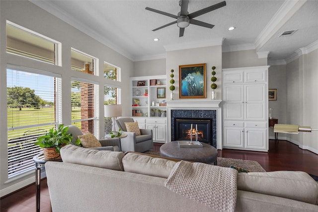 living area with visible vents, ceiling fan, a high end fireplace, crown molding, and dark wood-type flooring