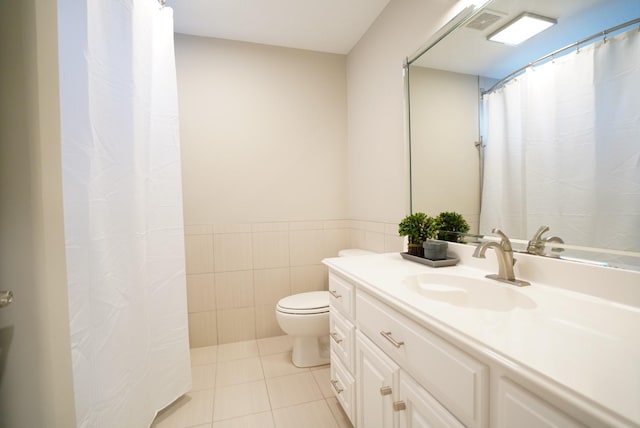 bathroom with vanity, tile patterned flooring, toilet, visible vents, and tile walls