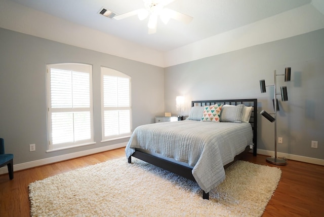 bedroom featuring ceiling fan, visible vents, baseboards, and wood finished floors