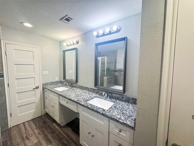 3060 Noble St, Houston, TX 77026 - bathroom with a sink, a stall shower, wood finished floors, and a textured ceiling