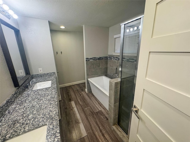 3060 Noble St, Houston, TX 77026 - bathroom featuring vanity, a textured ceiling, a shower stall, a freestanding bath, and wood finished floors