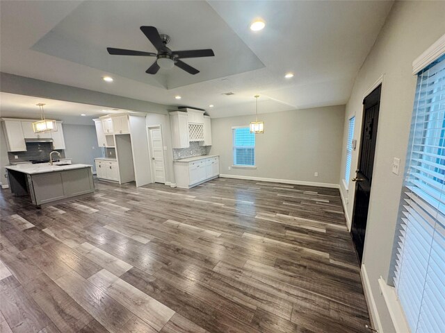 3060 Noble St, Houston, TX 77026 - unfurnished living room with a ceiling fan, recessed lighting, a raised ceiling, baseboards, and dark wood-style floors