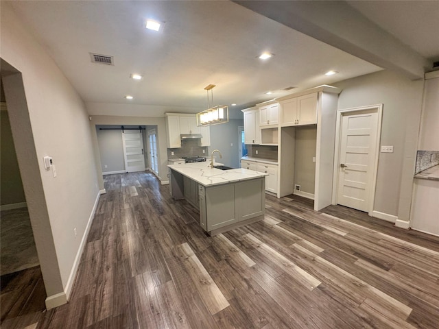 3060 Noble St, Houston, TX 77026 - kitchen featuring white cabinetry, visible vents, a barn door, under cabinet range hood, and dark wood-style floors