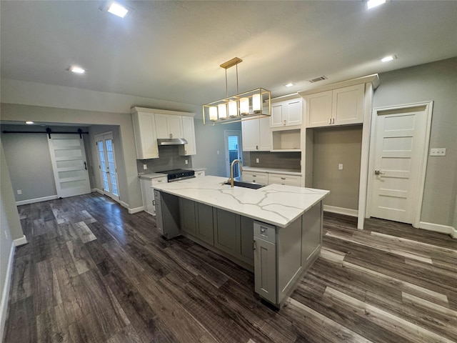 3060 Noble St, Houston, TX 77026 - kitchen with visible vents, under cabinet range hood, a kitchen island with sink, a sink, and electric stove