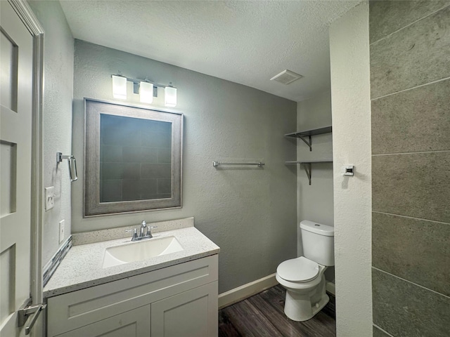 3060 Noble St, Houston, TX 77026 - bathroom with vanity, a textured ceiling, toilet, visible vents, and wood finished floors