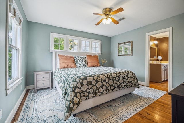 bedroom with baseboards, visible vents, multiple windows, and wood finished floors