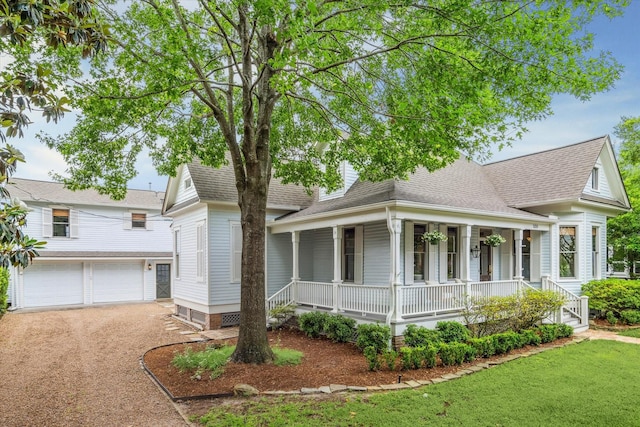 farmhouse inspired home featuring covered porch, driveway, a front yard, roof with shingles, and an attached garage