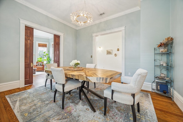 dining space featuring an inviting chandelier, baseboards, wood finished floors, and visible vents