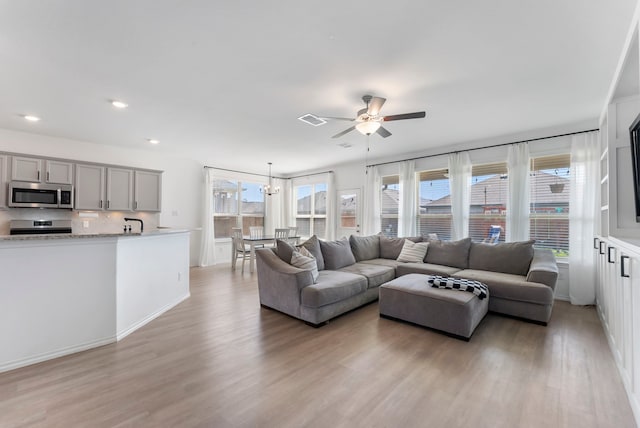 23830 Via Leoni Dr, New Caney, TX 77357 - living room with ceiling fan, light wood-style flooring, recessed lighting, baseboards, and a chandelier