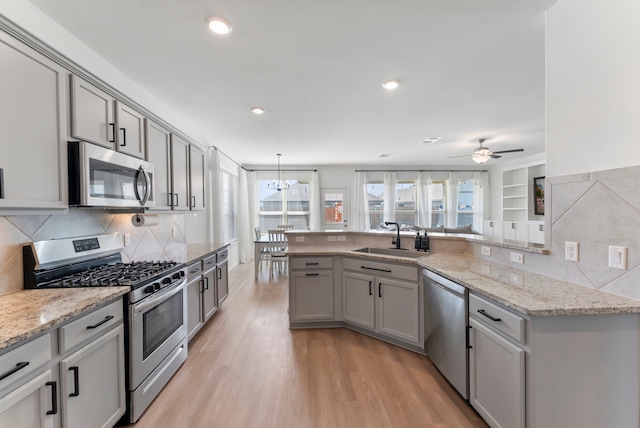 23830 Via Leoni Dr, New Caney, TX 77357 - kitchen with stainless steel appliances, a sink, gray cabinets, light wood-type flooring, and recessed lighting