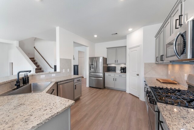 23830 Via Leoni Dr, New Caney, TX 77357 - kitchen with stainless steel appliances, a sink, gray cabinets, light wood-type flooring, and recessed lighting