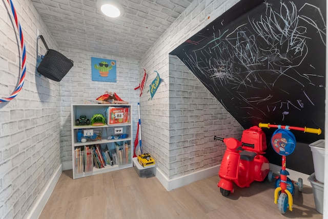 23830 Via Leoni Dr, New Caney, TX 77357 - recreation room with brick wall, wood finished floors, and baseboards