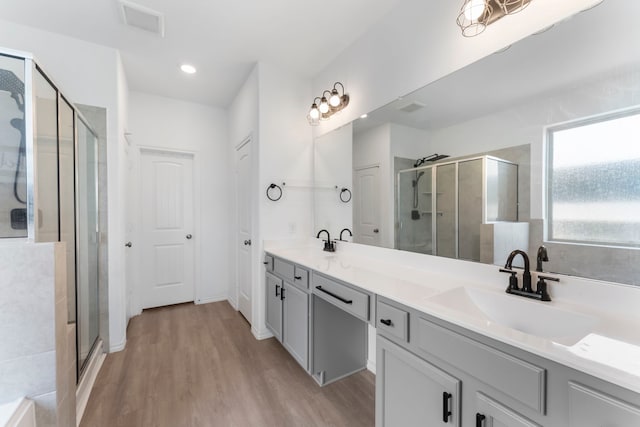 23830 Via Leoni Dr, New Caney, TX 77357 - full bathroom with wood finished floors, a shower stall, double vanity, and recessed lighting