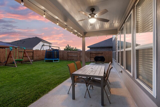 23830 Via Leoni Dr, New Caney, TX 77357 - patio terrace at dusk with outdoor dining space, a trampoline, and ceiling fan