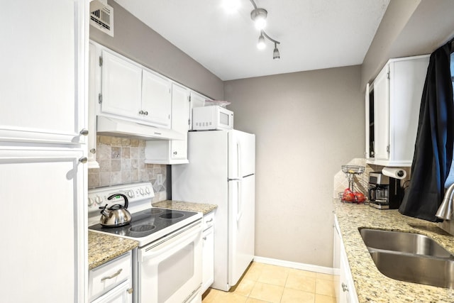 kitchen with white appliances, tasteful backsplash, visible vents, under cabinet range hood, and a sink
